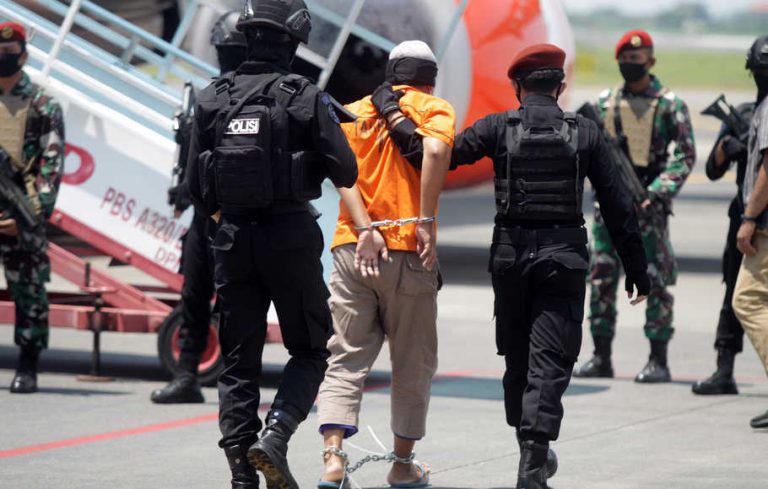 Personel Densus 88 Anti Teror membawa terduga teroris menuju ke pesawat udara di Bandara Internasional Juanda, Sidoarjo, Jawa Timur, Kamis (18/3/2021).