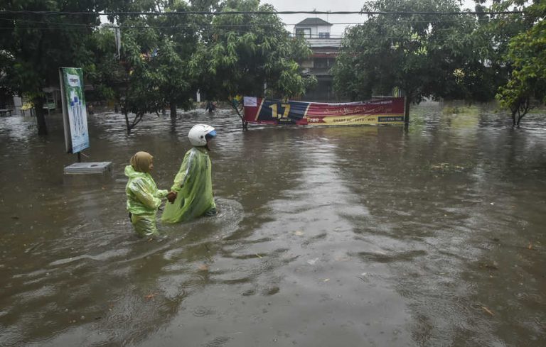 Seorang murid sekolah mendorong motor saat menerobos genangan air di, Rawalumbu, Bekasi, Jawa Barat, Senin (18/10/2021)