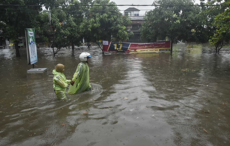 Seorang murid sekolah mendorong motor saat menerobos genangan air di, Rawalumbu, Bekasi, Jawa Barat, Senin (18/10/2021)